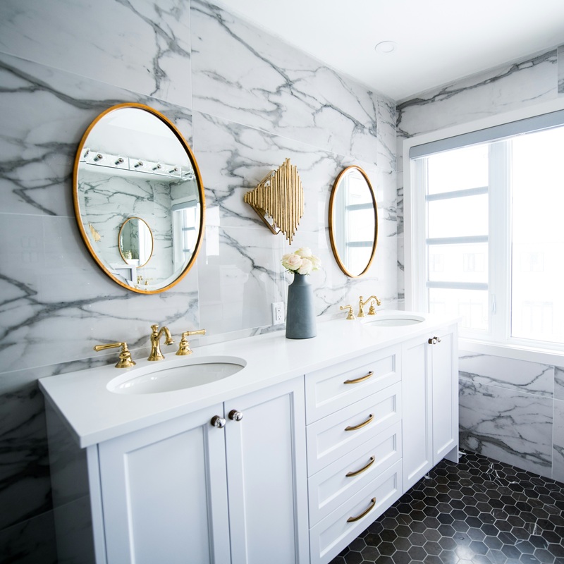 Bright marble and gold bathroom with two sinks and two mirrors